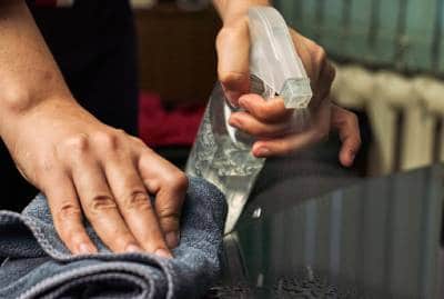 person holding spray bottle and microfiber towel